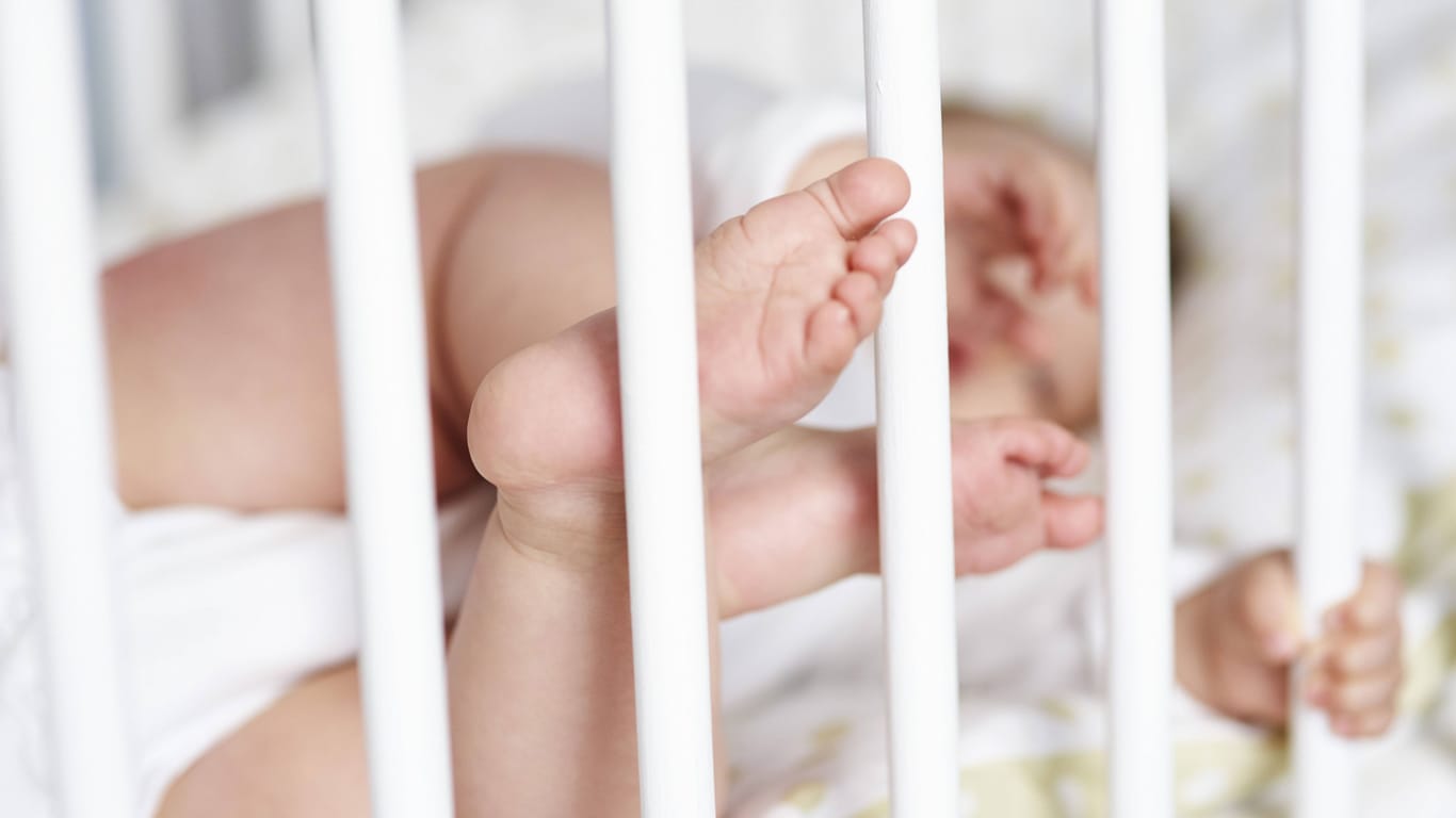 Ein Baby streckt seine Füße durch die Gitterstäbe seines Bettes (Symbolbild): Der Mutter war es nicht gelungen, ihr Kind zu befreien.