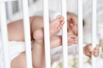 Ein Baby streckt seine Füße durch die Gitterstäbe seines Bettes (Symbolbild): Der Mutter war es nicht gelungen, ihr Kind zu befreien.