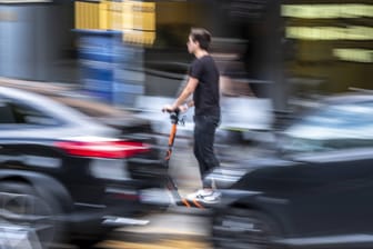 Ein Mann fährt mit einem E-Scooter durch Berlin (Symbolfoto): Ohne ein gültiges Kennzeichen dürfen sie nicht im öffentlichen Straßenverkehr gefahren werden.