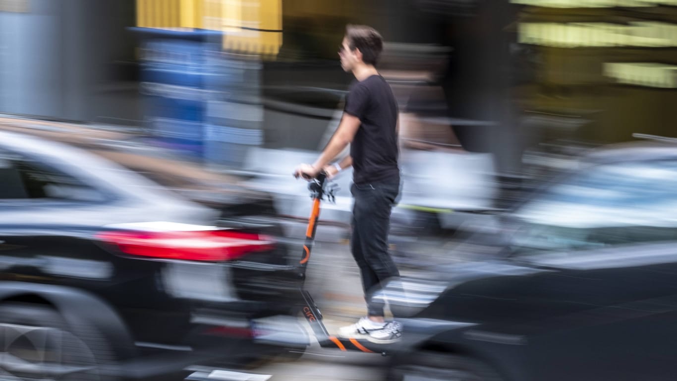 Ein Mann fährt mit einem E-Scooter durch Berlin (Symbolfoto): Ohne ein gültiges Kennzeichen dürfen sie nicht im öffentlichen Straßenverkehr gefahren werden.