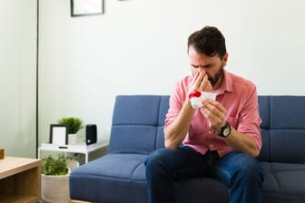 Mann mit Nasenbluten auf dem Sofa