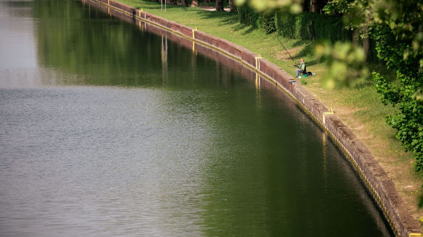 Ein Angler sitzt in der Sonne am Rhein-Herne-Kanal.