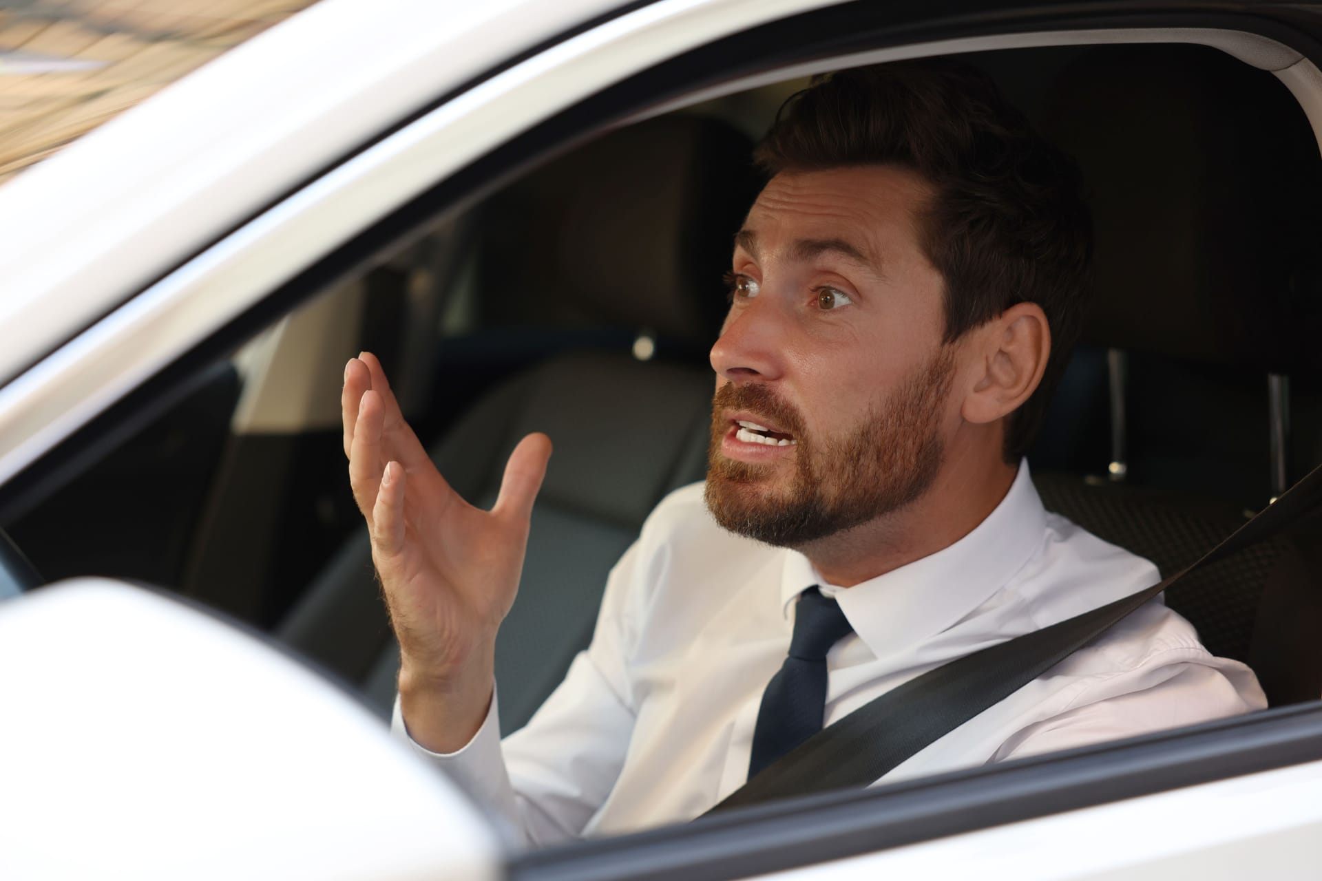 Stressed driver in his car, view from outside. Stuck in traffic jam