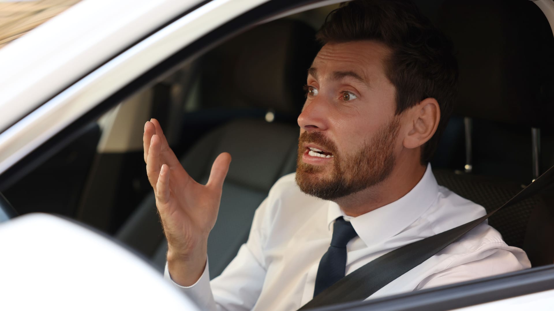 Stressed driver in his car, view from outside. Stuck in traffic jam