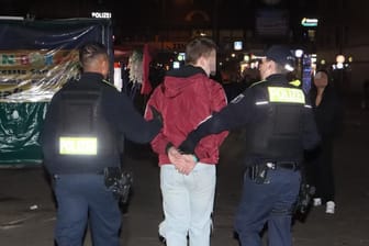 Polizisten führen einen der jungen Männer ab: Alle drei Angreifer kamen in Gewahrsam.