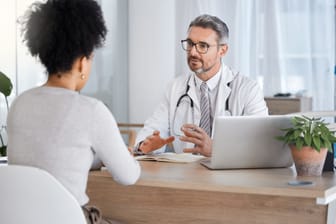 Junge Frau im Gespräch mit einem Arzt