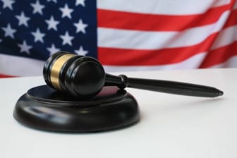 Hammer vor US-Flagge (Symbolbild): Das Urteil eines Militärgerichts gegen einen US-Sergeant ist gefallen.