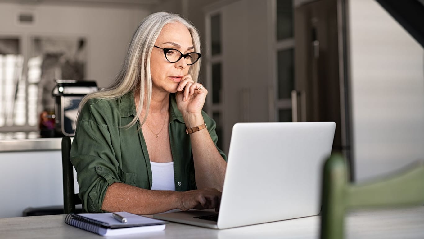 Ältere Frau am Laptop: Früher galt die Regel, den Aktienanteil mit steigendem Alter zu reduzieren – und heute?