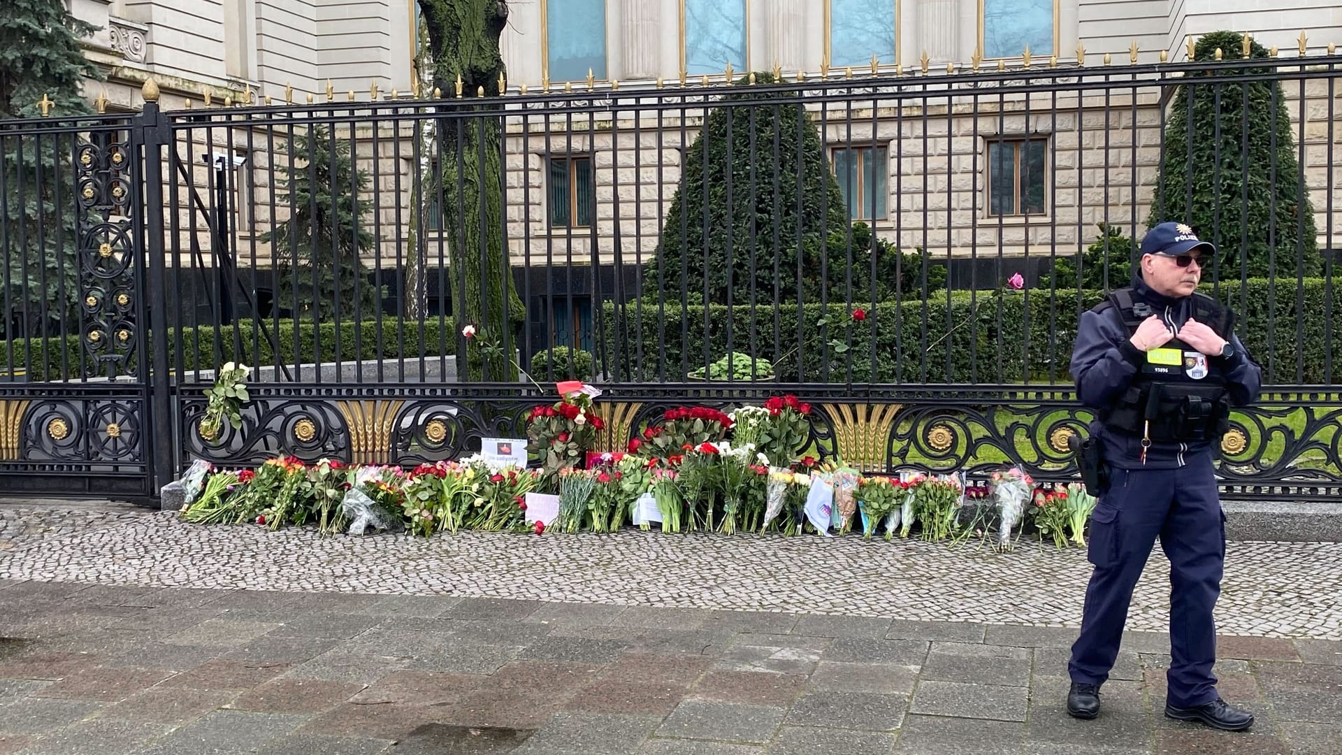 Niederlegte Blumen vor der russischen Botschaft in Berlin: Ein Polizist nimmt die Blumen der Trauernden entgegen.