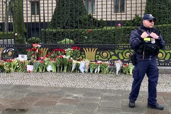 Niederlegte Blumen vor der russischen Botschaft in Berlin: Ein Polizist nimmt die Blumen der Trauernden entgegen.
