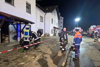 Einsatzkräfte der Feuerwehr stehen nach einem Brand vor einem Wohnkomplex in der Oberpfalz. Bei dem Brand sind mehr als 30 Menschen durch Rauch verletzt worden.