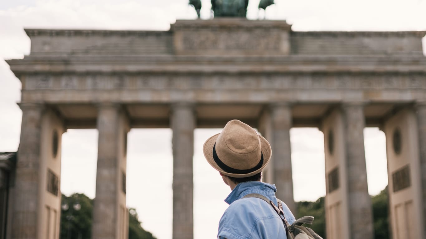 Ein Mann steht vor dem Brandenburger Tor in Berlin (Symbolbild): Eine Plattform hat ausgewertet, wie viel Geld man braucht, um in Berlin über die Runden zu kommen.