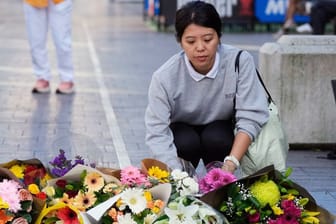 Eine Frau bringt Blumen zu einer improvisierten Gedenkstätte an der Bondi Junction. Hier hatte ein misogyner Attentäter im Einkaufszentrum fünf Frauen und einen Mann ermordet.