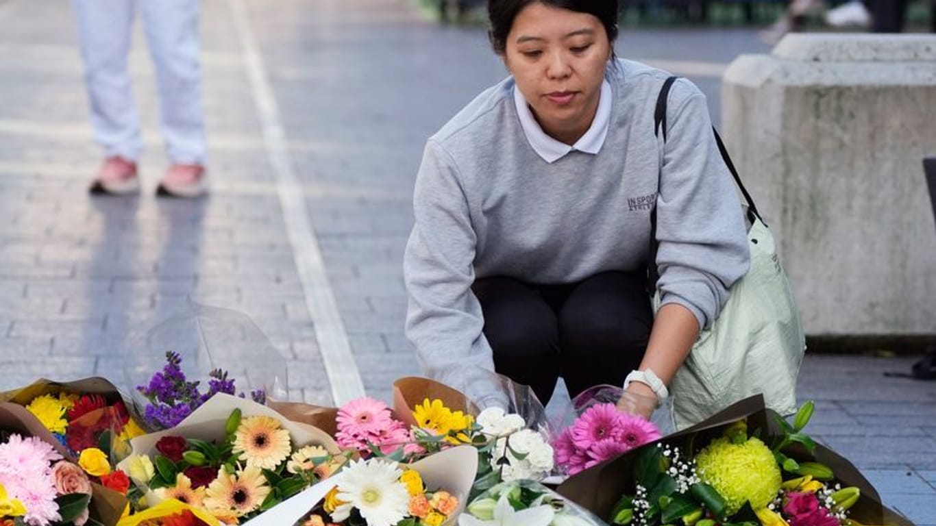 Eine Frau bringt Blumen zu einer improvisierten Gedenkstätte an der Bondi Junction. Hier hatte ein misogyner Attentäter im Einkaufszentrum fünf Frauen und einen Mann ermordet.