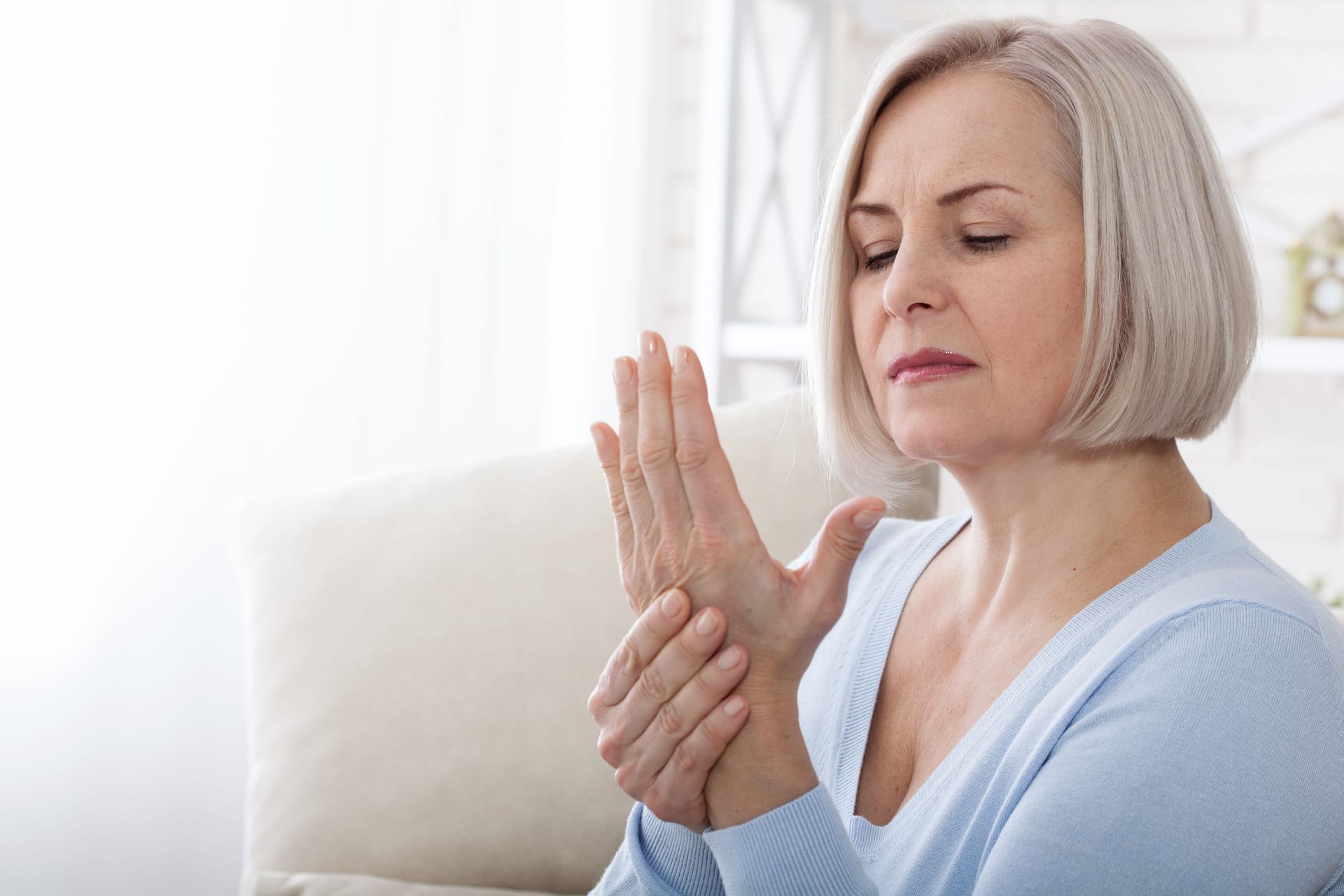 Frau mit Beschwerden in der Hand: Das Karpaltunnelsyndrom kann mit mehr oder weniger starken Beschwerden in der Hand einhergehen. Bis zu einem gewissen Grad lassen sich diese womöglich mit Hausmitteln lindern.