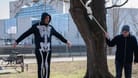 07.03.2024, Berlin, Deutschland, Europa - Der deutsche Klimaaktivist Wolfgang Wolli Metzeler-Kick traegt ein Skelettkostuem und steht mit einer Schlinge um den Hals auf einem schmelzenden Eisblock neben einem Baum, waehrend im Hintergrund das Bundeskanzleramt zu sehen ist.
