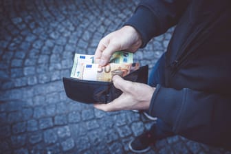 Ein Mann hält ein Portemonnaie in der Hand (Symbolbild): Durch die Dokumente konnte der Besitzer ermittelt und informiert werden.