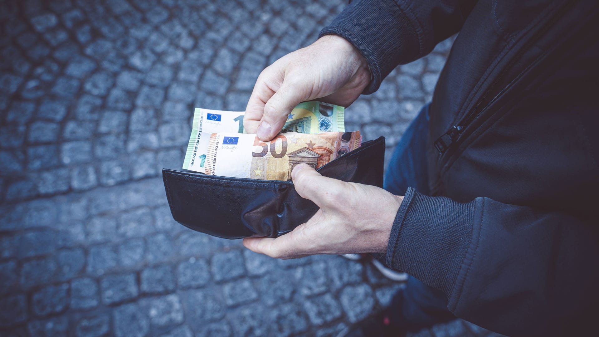 Ein Mann hält ein Portemonnaie in der Hand (Symbolbild): Durch die Dokumente konnte der Besitzer ermittelt und informiert werden.