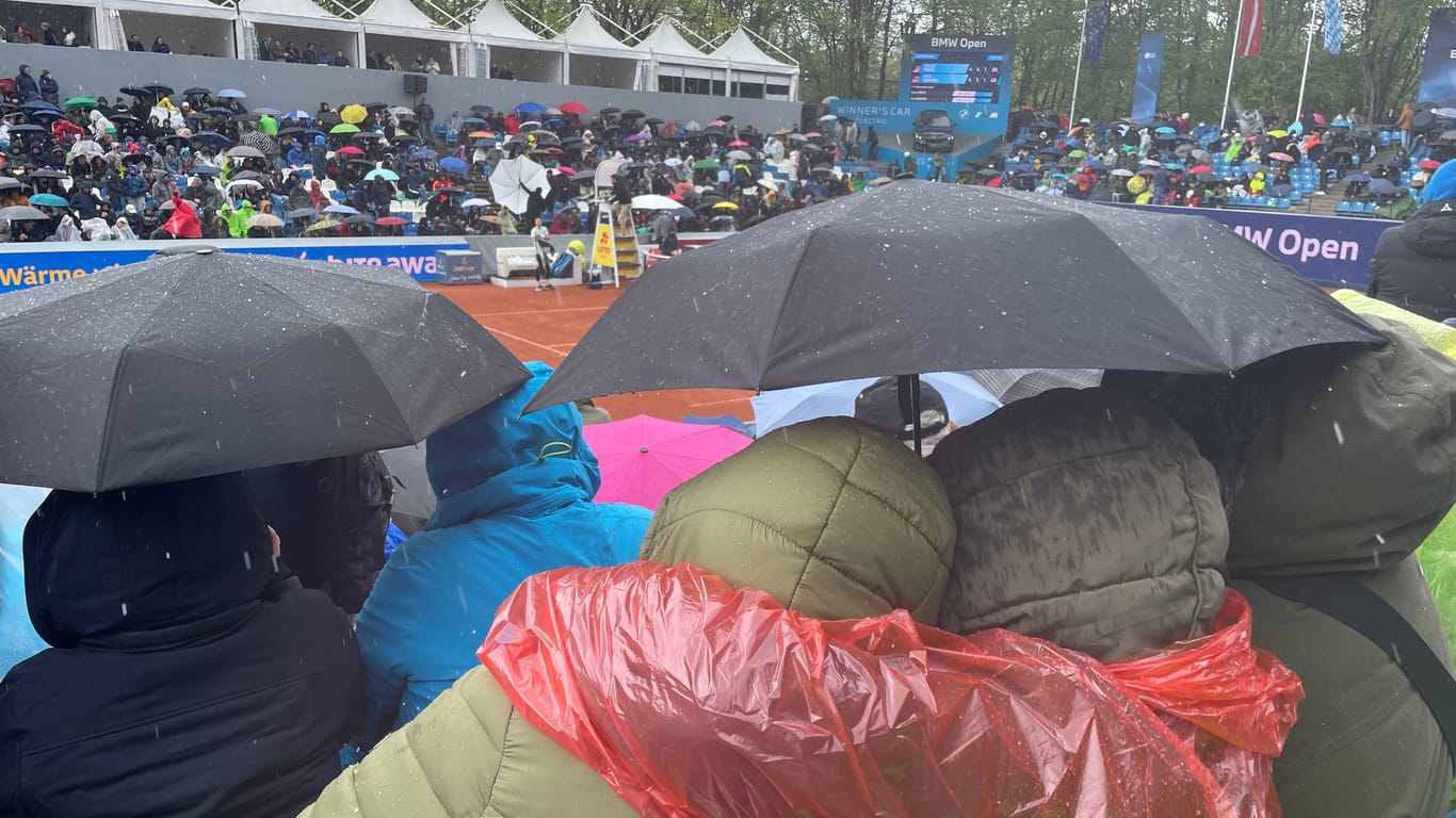 Ausgestattet mit Schirmen und Regenponchos: Während der Spielunterbrechungen versuchen die Fans, sich aneinander zu wärmen.