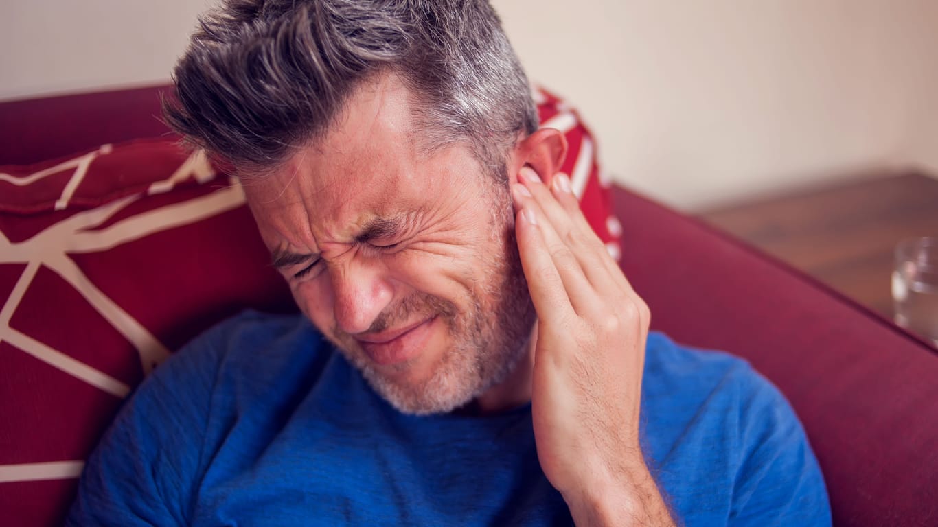 Mann mit Ohrenschmerzen: Eine Gehörgangsentzündung ist oft mit starken Ohrenschmerzen verbunden.