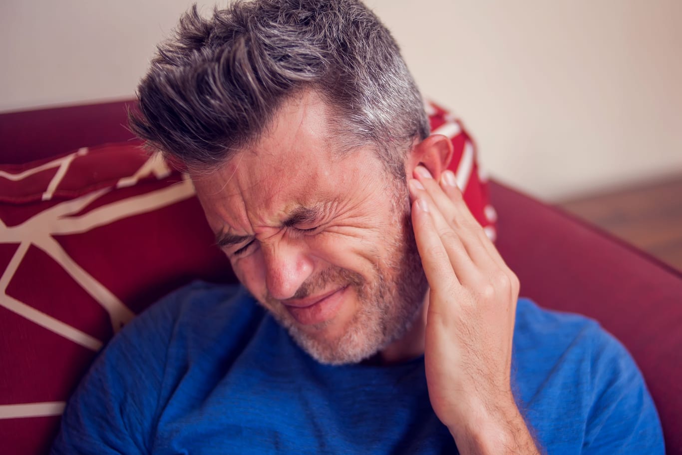 Mann mit Ohrenschmerzen: Eine Gehörgangsentzündung ist oft mit starken Ohrenschmerzen verbunden.