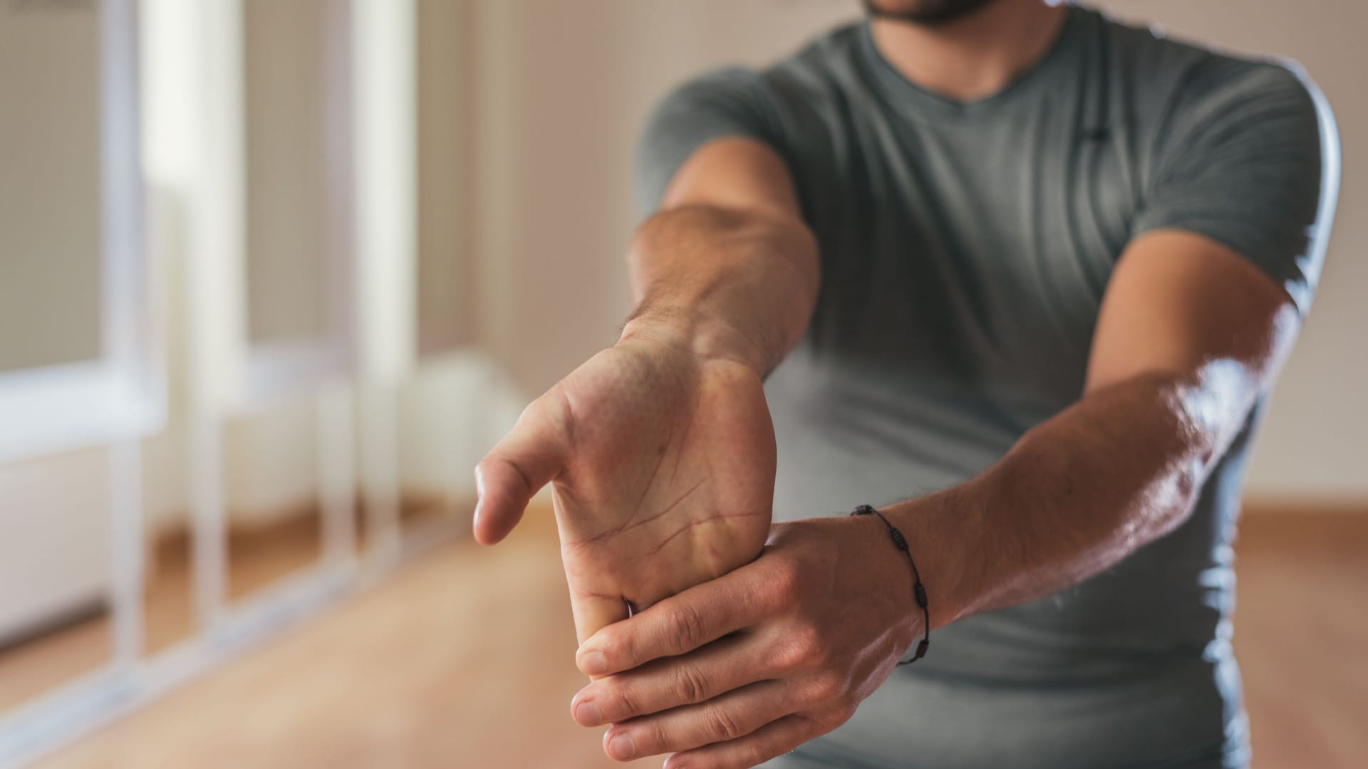 Ein Mann dehnt die Unterarmmuskeln: Ob sich das Karpaltunnelsyndrom allein mit Übungen behandeln lässt, ist fraglich. Sie können die Therapie jedoch unterstützen.