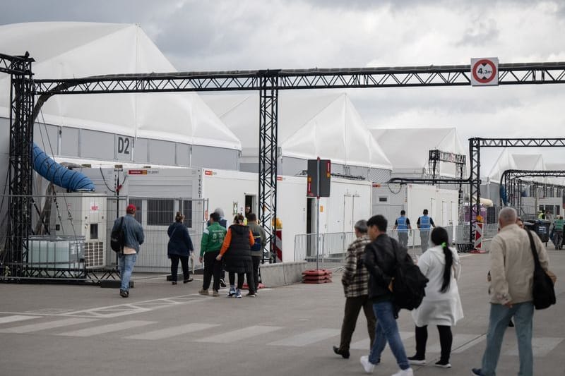 Bewohner und Mitarbeiter gehen im Ankunftszentrum am ehemaligen Flughafen Tegel in Richtung der Leichtbauhallen.