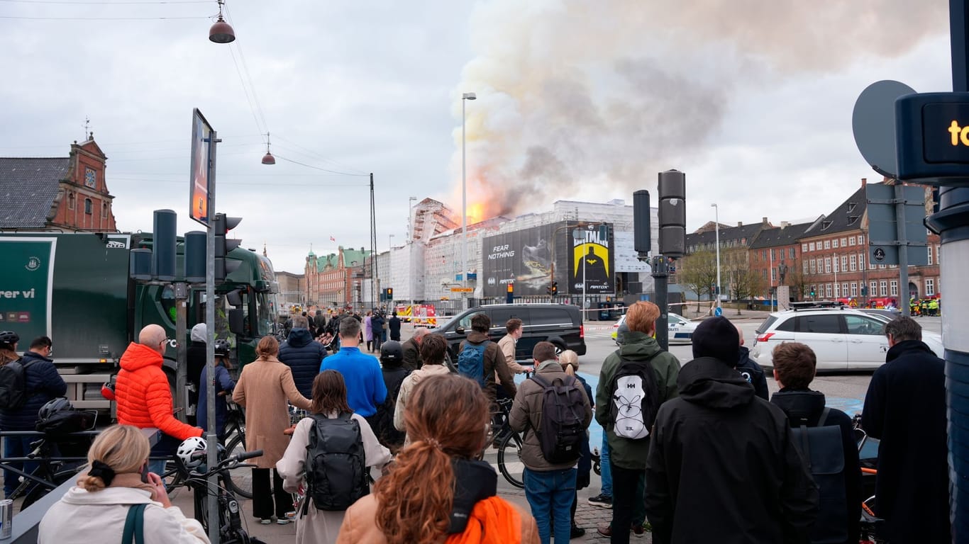 Dänemark, Kopenhagen: Menschen beobachte, wie Feuer und Rauch aus der Alten Börse, "Boersen" bei einem Brand in Kopenhagen aufsteigen.