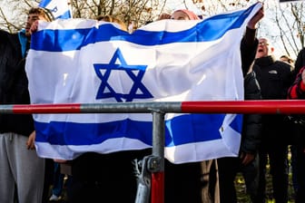 Personen halten eine Israel-Flagge (Archivbild): Am Sonntag ist eine Solidaritätskundgebung für Israel am Brandenburger Tor geplant.