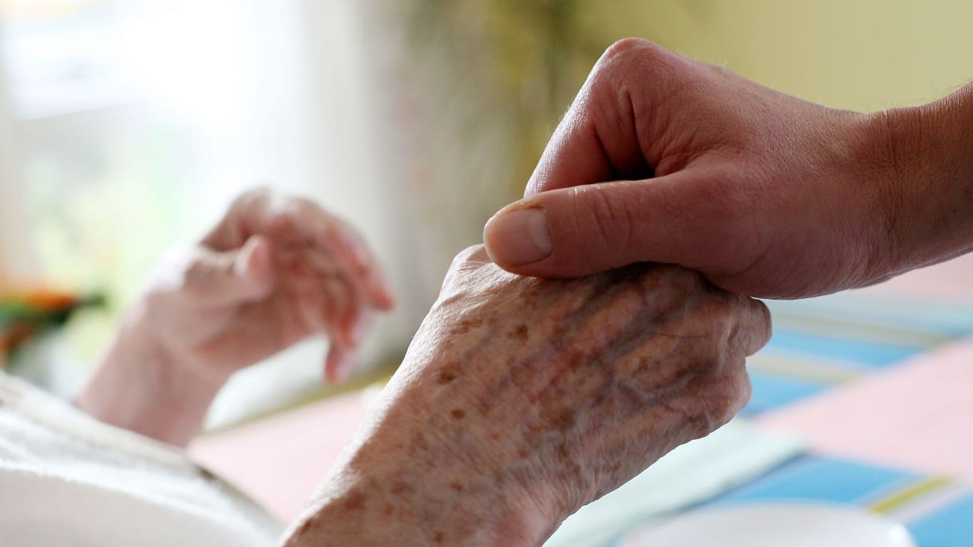 Ein Pfleger hält in einem Pflegeheim die Hand einer Bewohnerin (Symbolbild): In Bremen fehlen Pflegekräfte mehr als andernorts.