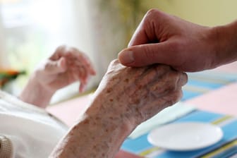 Ein Pfleger hält in einem Pflegeheim die Hand einer Bewohnerin (Symbolbild): In Bremen fehlen Pflegekräfte mehr als andernorts.