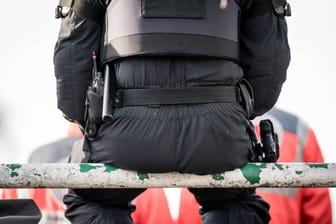 Ein Polizist sitzt auf einer Metallstange in einem Stadion (Symbolfoto): Die Ermittler aus Bremen halten sich zurzeit bedeckt und nennen keine weiteren Details.