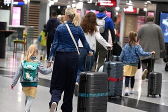 Reisende schieben ihre Koffer am Flughafen Düsseldorf zur Gepäckaufgabe (Archivbild): Hier und am Flughafen Köln/ Bonn ist zum Ferienende besonders viel los.