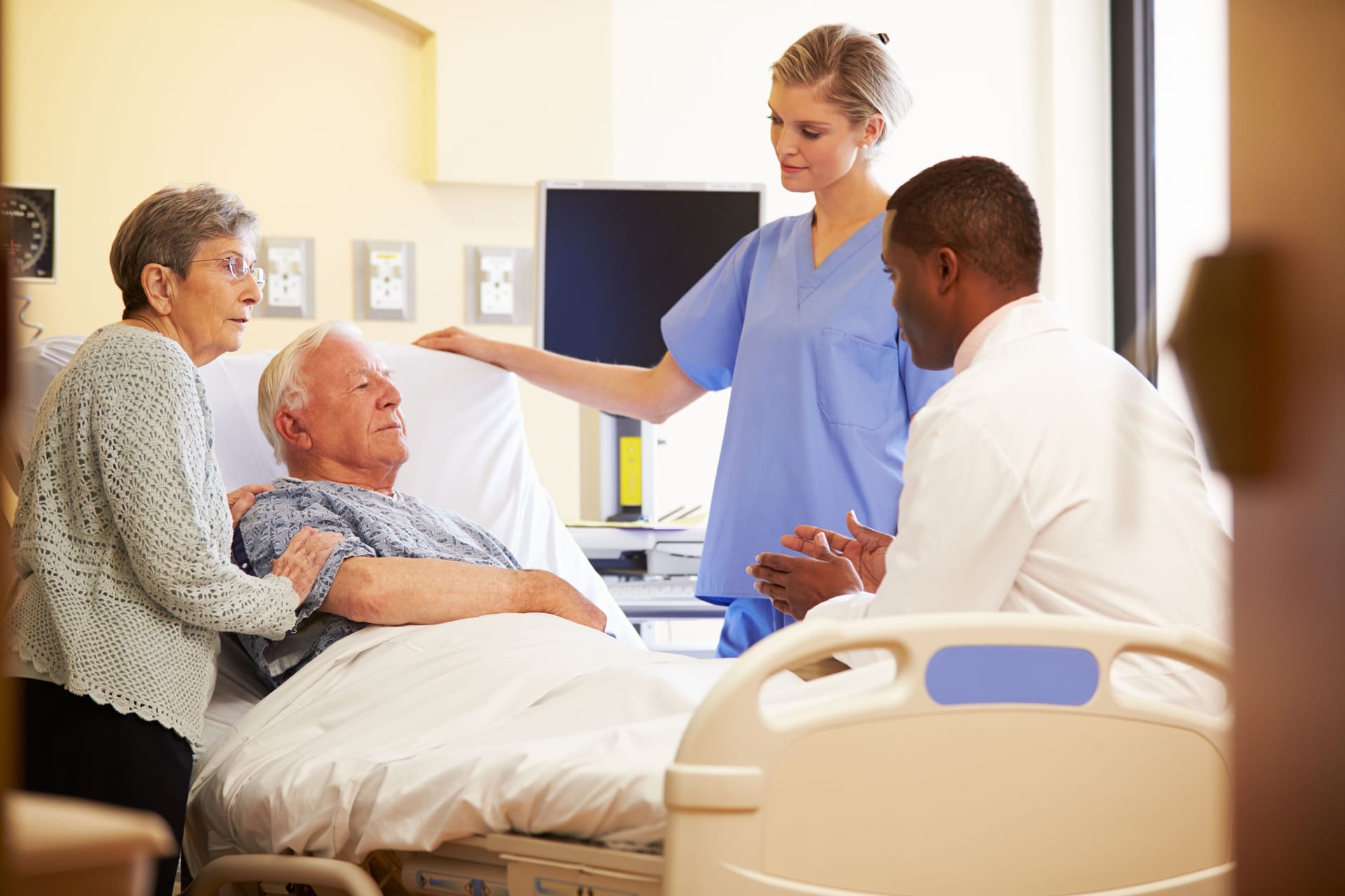 Ein Mann sitzt im Krankenhausbett und spricht mit einem Arzt.