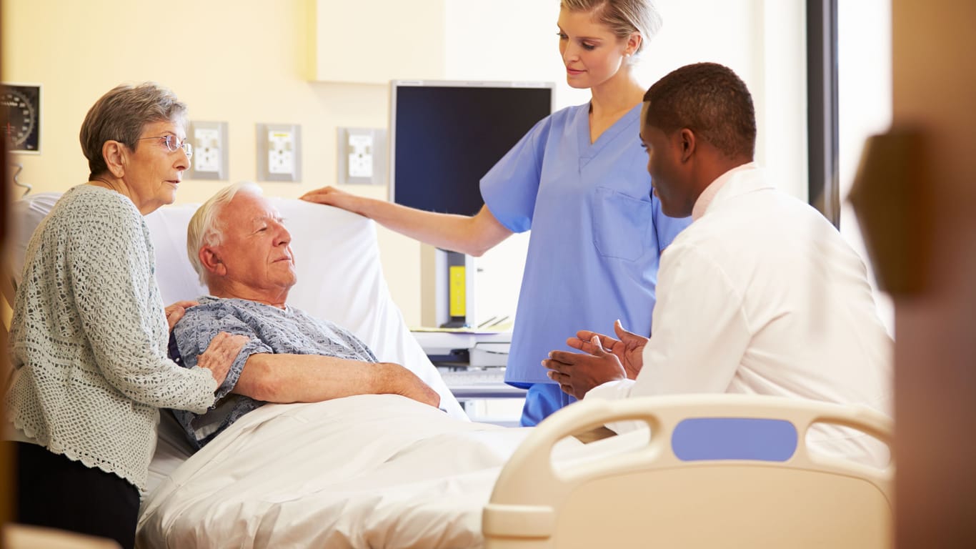 Ein Mann sitzt im Krankenhausbett und spricht mit einem Arzt.