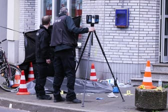 Düsseldorf: Zwei Männer sichern Spuren und Beweise neben einer abgedeckten Leiche vor eine Kneipe.