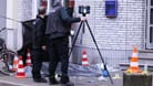 Düsseldorf: Zwei Männer sichern Spuren und Beweise neben einer abgedeckten Leiche vor eine Kneipe.