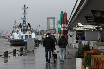 Passanten gehen an den Landungsbrücken entlang (Symbolbild): Windgeschwindigkeiten von bis zu 85 km/h werden an der Nordseeküste erwartet.
