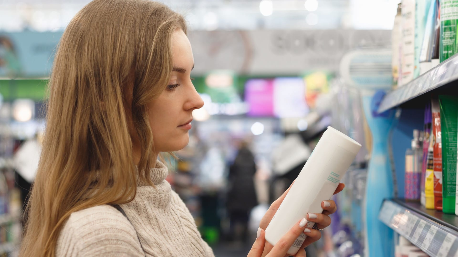 Eine Frau liest das Etikett eines Kosmetikprodukts