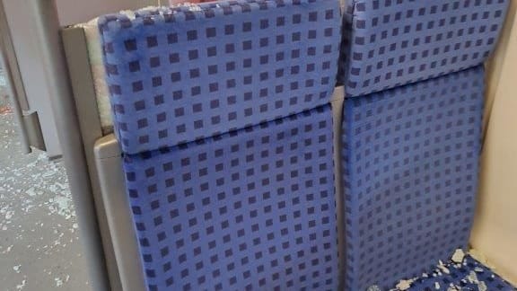Scherben der zerstörten Scheibe liegen auf einem Sitz: Eine Person wurde bei dem Vorfall leicht verletzt.