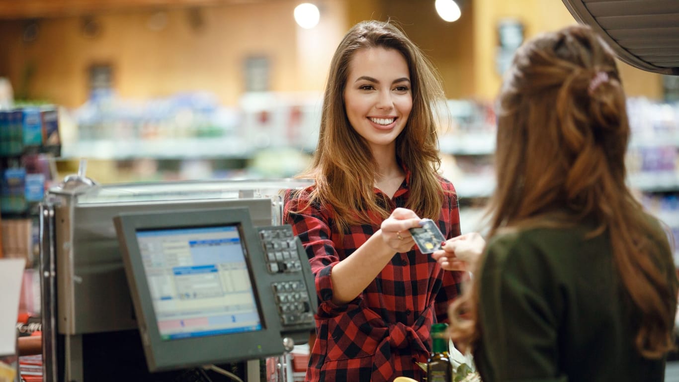Frau bezahlt an Supermarktkasse mit Kreditkarte