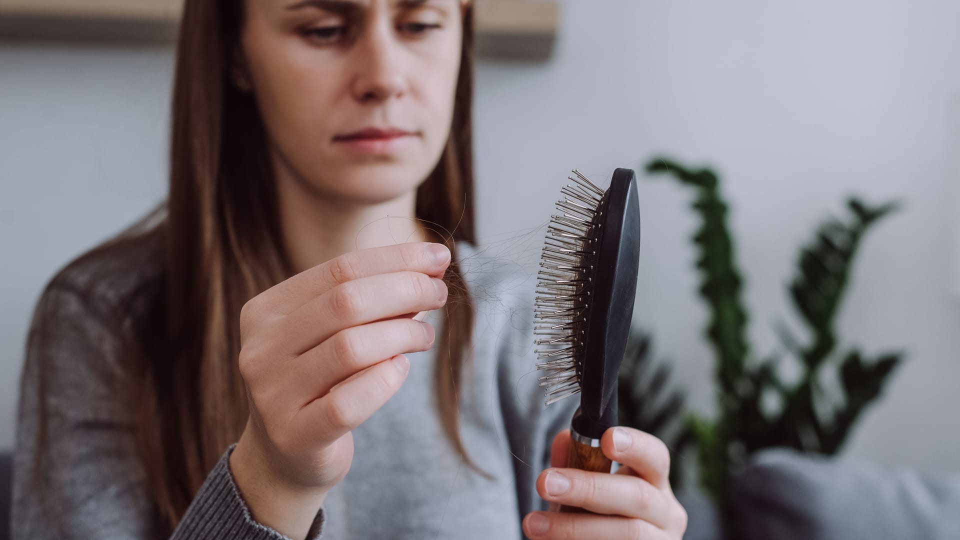 Eine Frau zieht Haare aus der Bürste.