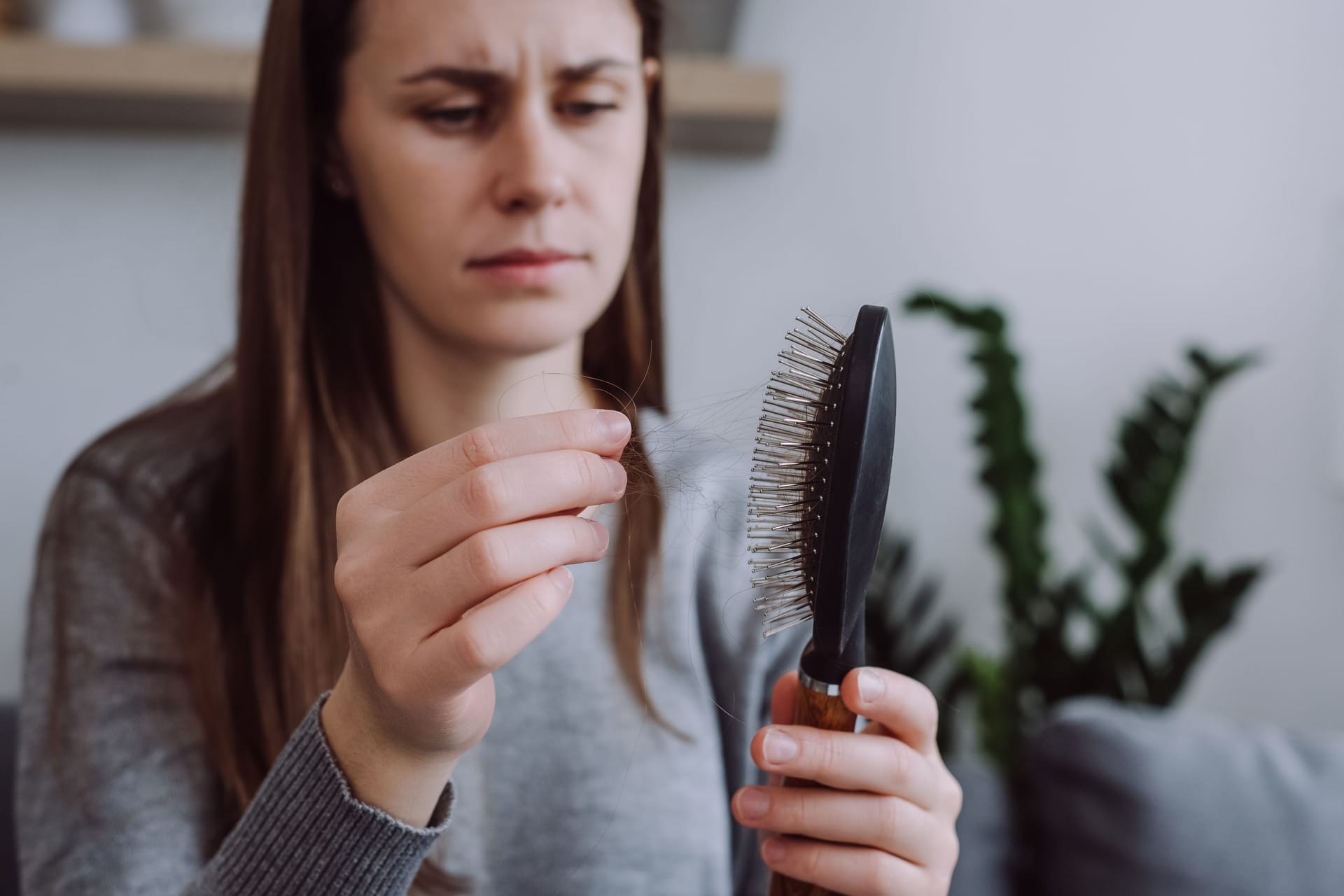 Eine Frau zieht Haare aus der Bürste.