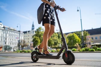 Frau fährt mit einem E-Scooter durch die Stadt