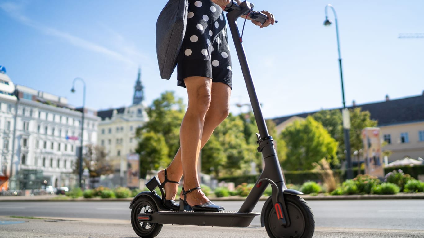 Frau fährt mit einem E-Scooter durch die Stadt