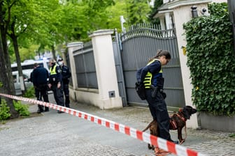 Beamten der Berliner Polizei suchen vor einem Haus an der Königsallee mit einem Spurensuchhund nach Spuren. Nach einer versuchten Brandstiftung an einem Auto auf einem Grundstück in Berlin-Grunewald ermittelt der polizeiliche Staatsschutz.