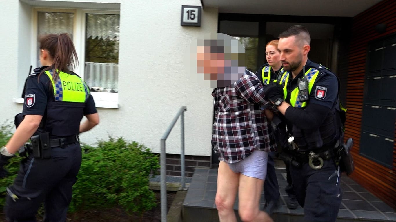 Polizisten nehmen einen Mann fest: Er soll in Hamburg-Hausbruch eine Frau schwer verletzt haben.