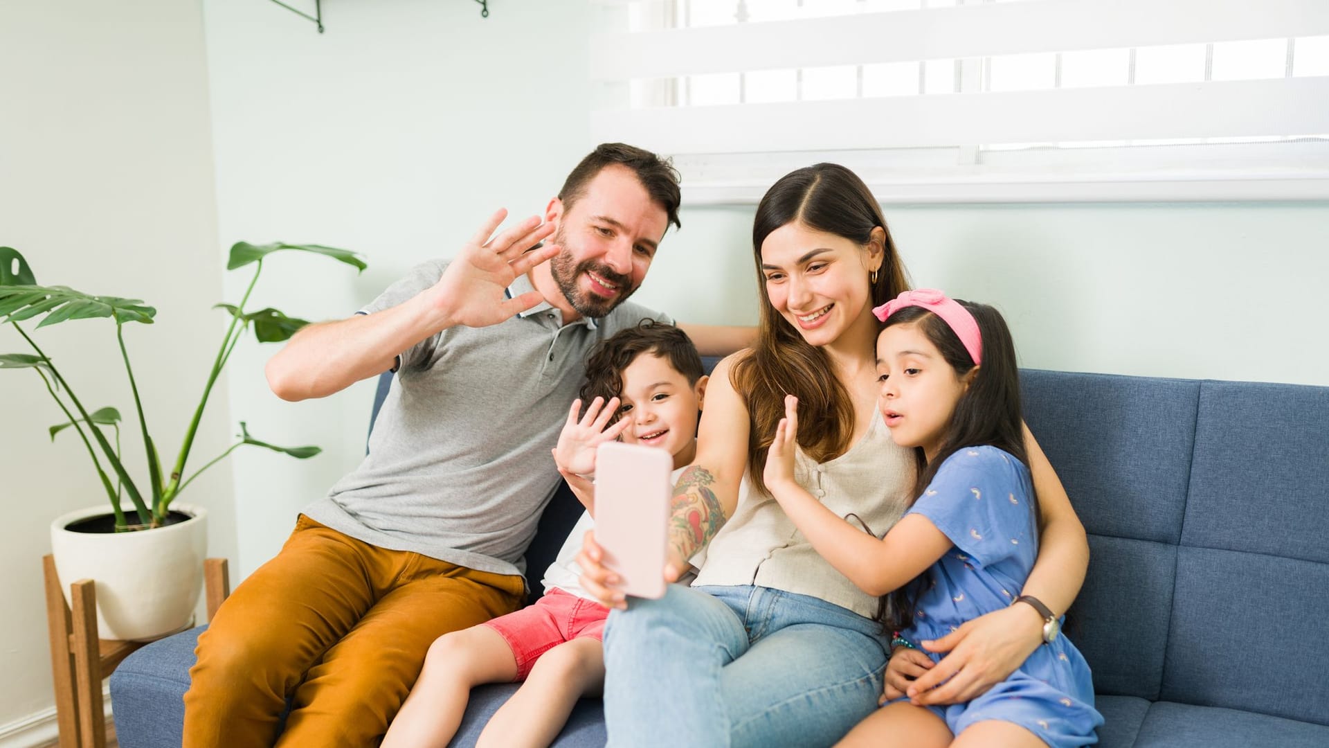 Familie, Mutter, Vater und zwei Kinder, sitzen auf dem Sofa und machen ein Selfie