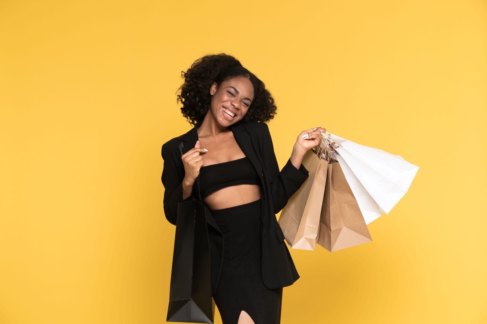 Young black woman laughing while posing with shopping bags