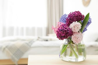 Beautiful hyacinths in glass vase on table indoors, space for text. Spring flowers